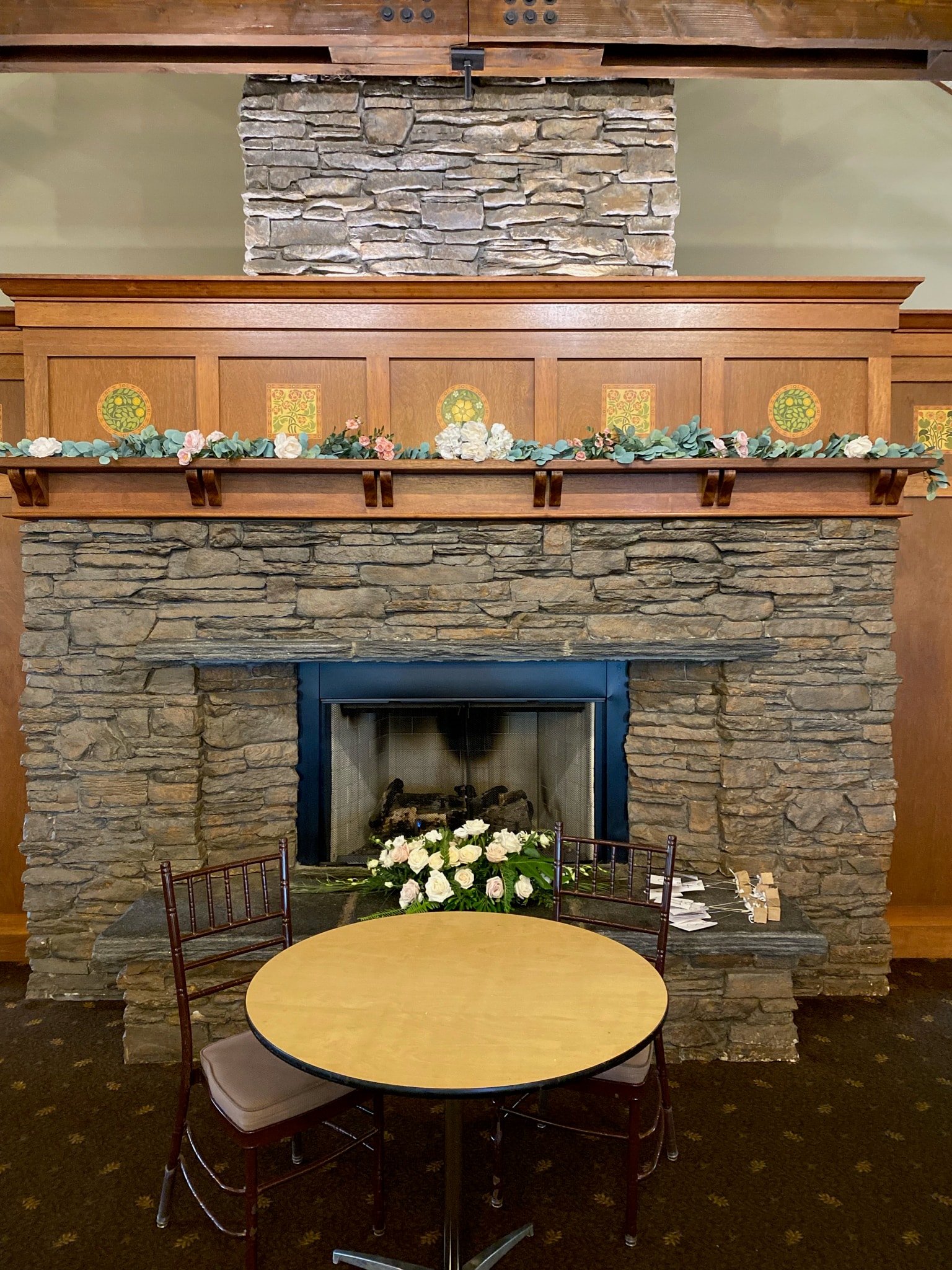 Stone fireplace with floral garland mantel and white rose arrangement at The Flint's wedding