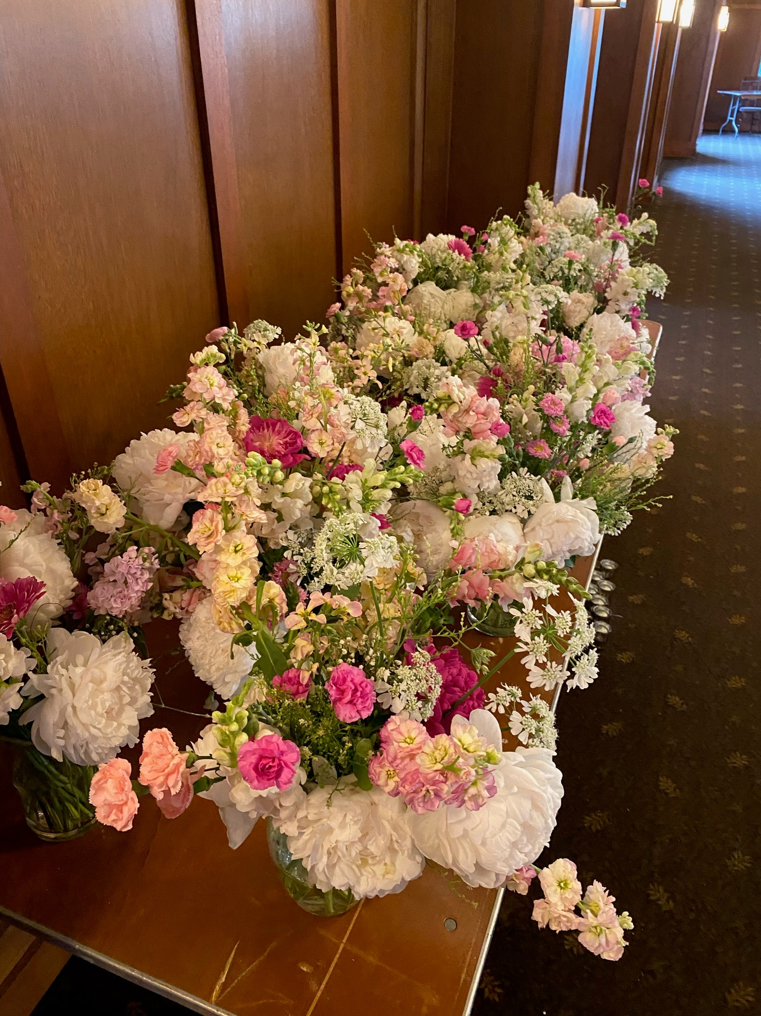 Stunning row of pink and white peony floral arrangements lining a corridor at The Flint's wedding