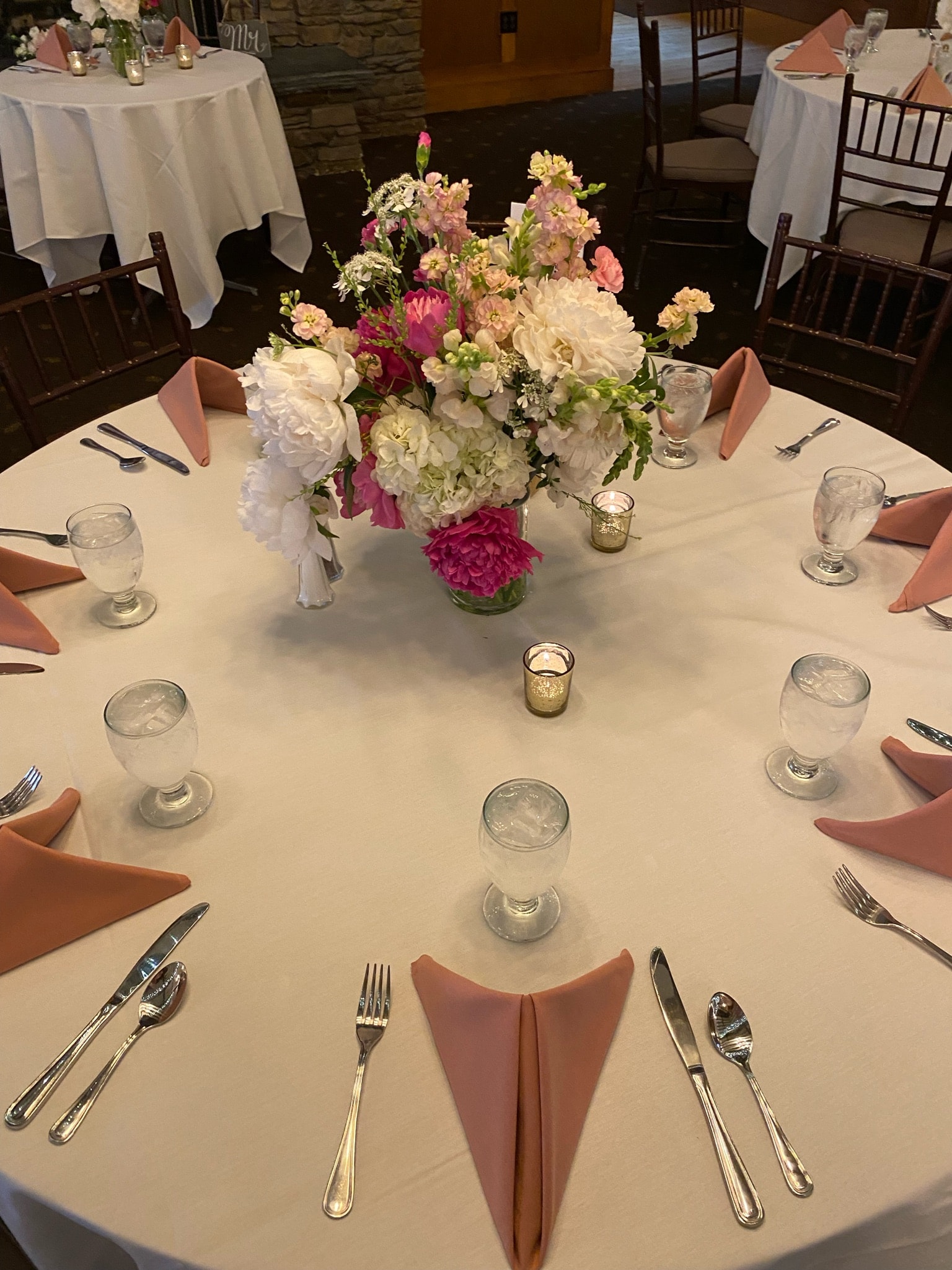 Elegant wedding table with pink and white floral centerpiece and coral napkins at The Flint's wedding