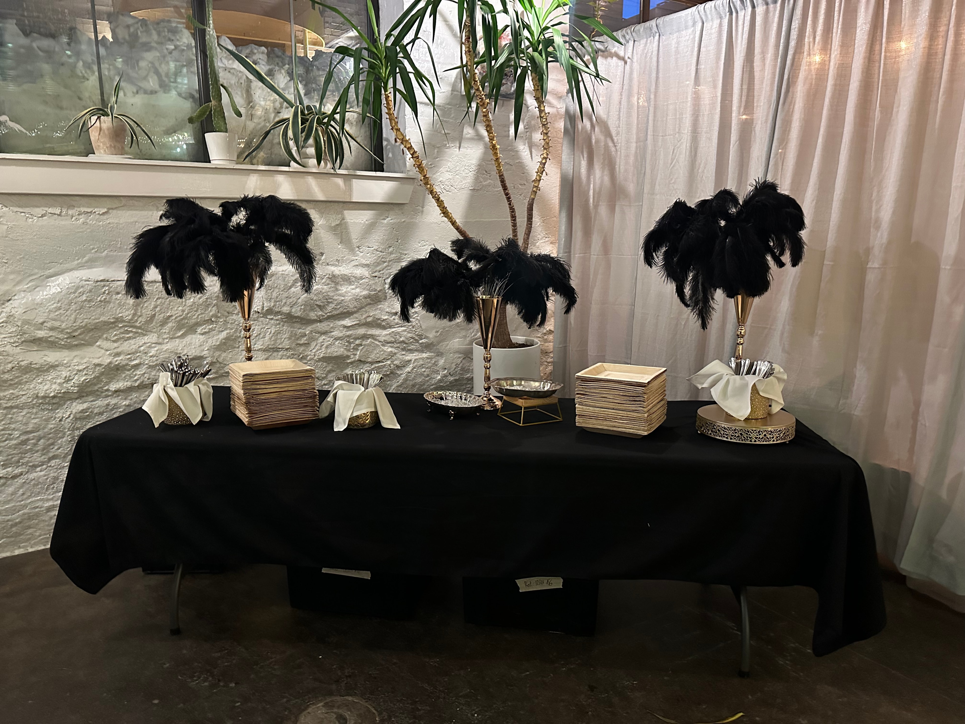 Black and gold Gatsby-themed table with black feather centerpieces and gold accents