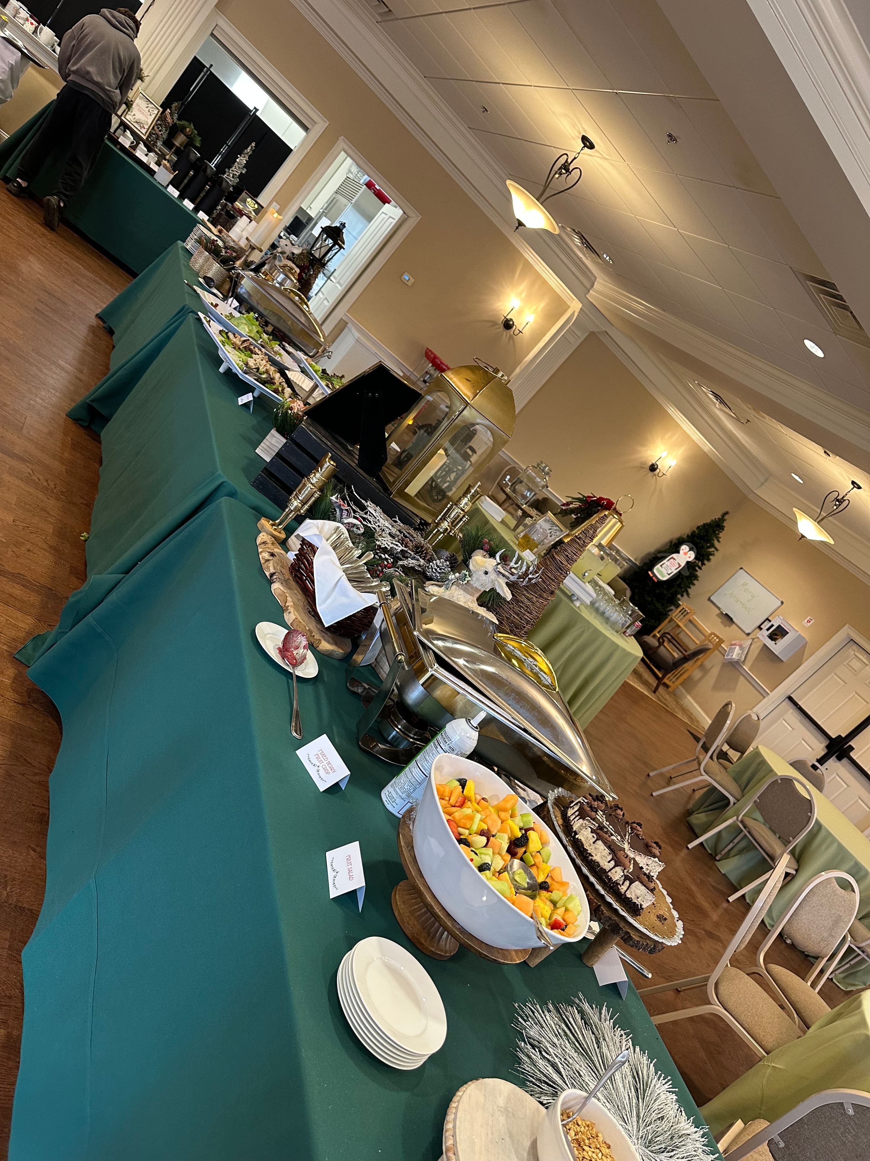 Holiday party buffet spread with chafing dishes, fruit salad, and seasonal décor