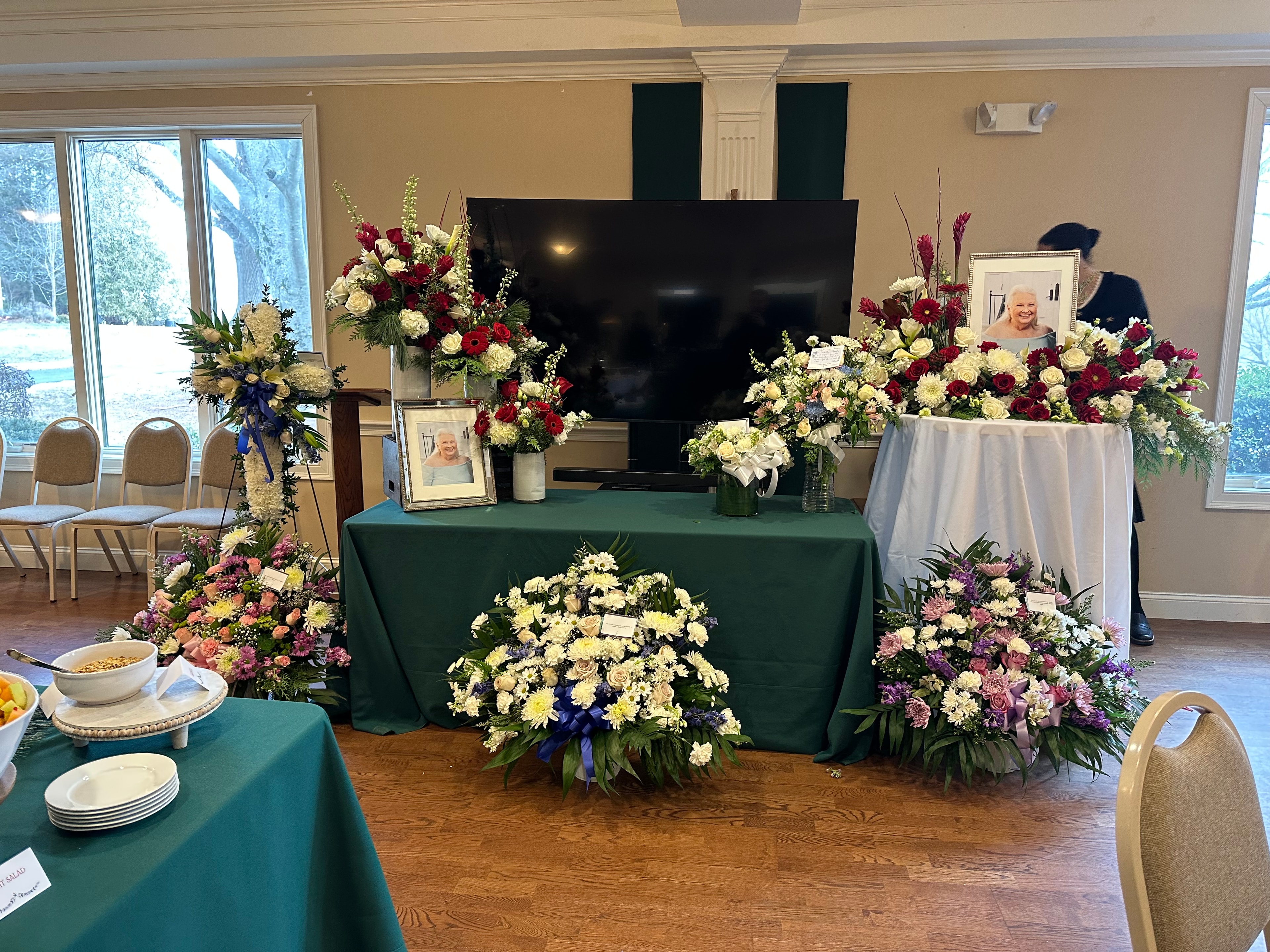Floral tribute display with abundant flower arrangements and framed photos at a celebration of life